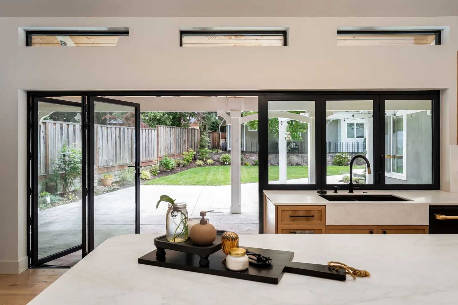 Bifold glass doors opening kitchen to backyard