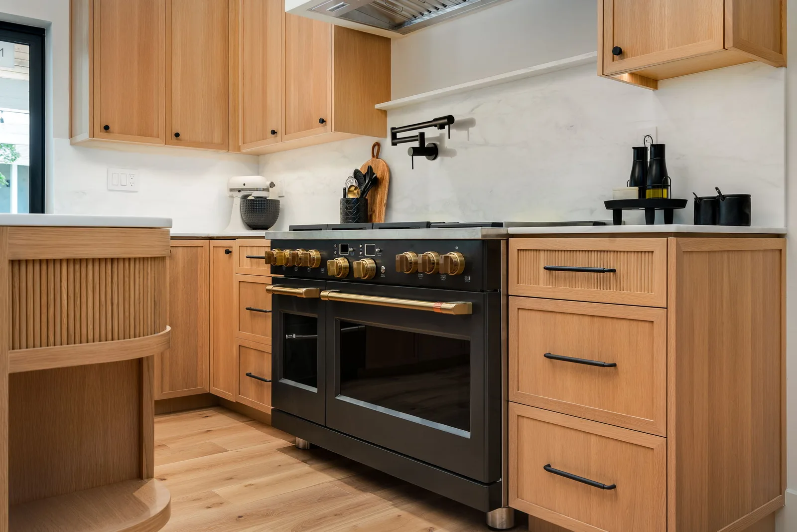 Black and brass professional range with fluted oak cabinetry